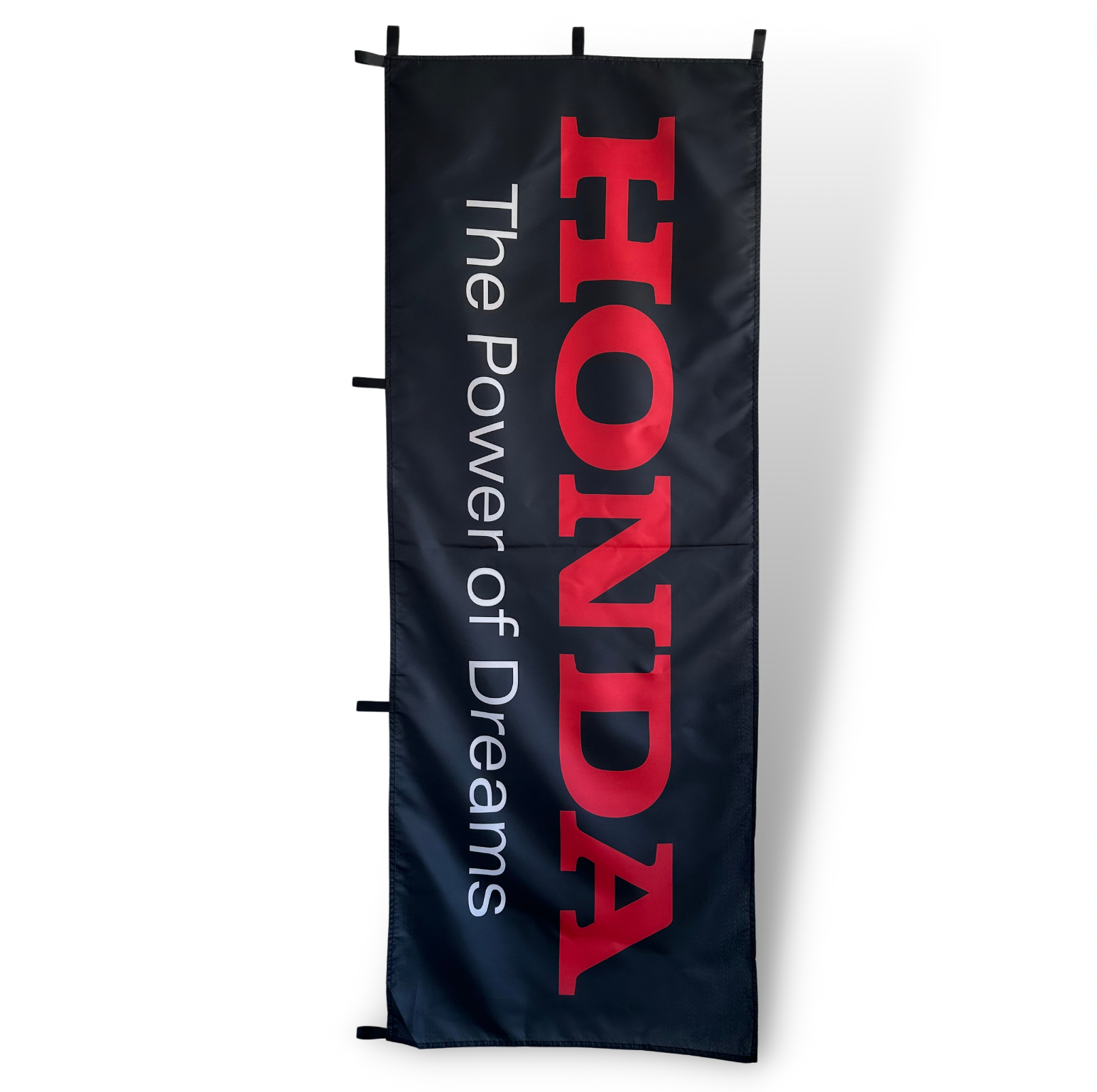 A Black Rectangular Flag with White Honda text and black The power of Dreams text underneath