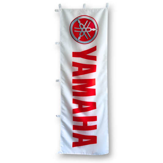 A rectangular flag with the Yamaha logo, predominantly white with red and black text, and a red circle at the top.